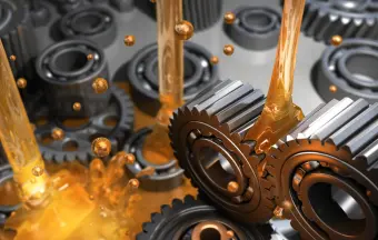 Metal gears and cogs with lubricating oil being applied, showing a close-up view of mechanical parts in operation.